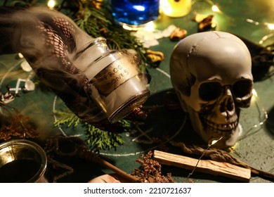 Witch Holding Jar With Frog Bones On Wizard Table