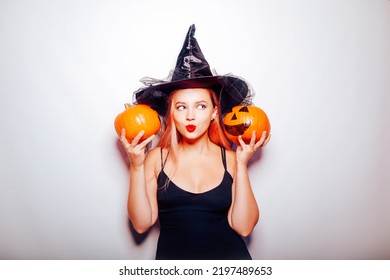 The Witch Listens To The Pumpkins, The Model Is Shocked. Woman With Hat And Black Dress, Halloween Party.