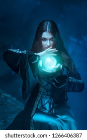 The witch with magic ball in her hands causes a spirits in cave