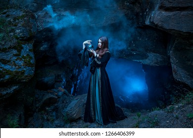 The witch with magic ball in her hands causes a spirits in cave