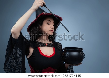 Witch using her magic wand to prepare a potion in her cauldron. Ideal for Halloween, potion brew, fairy tales, spells, and fantasy. Horizontal studio portrait with copy space.