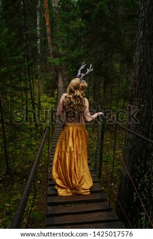 Witch wear a long skirt and walk at hanging wooden bridge. back view. 