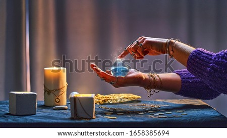 Witch woman with magic elixir potion bottle around candles and magical accessories during alchemy witchcraft