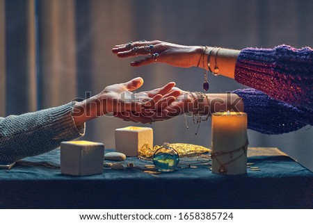 Witch woman spelling over hand palm during occult spiritual rite and divination ritual around candles and other magical accessories. Magic illustration 