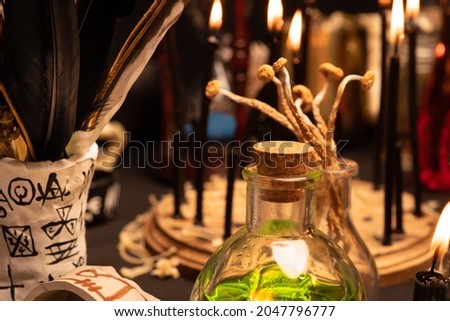 Witchcraft table set, selective focus at potion vial or glass bottle with magic liquid ingredient. Alchemy and esoteric items for magic cult at the background. Spiritual occultism and magic chemistry 