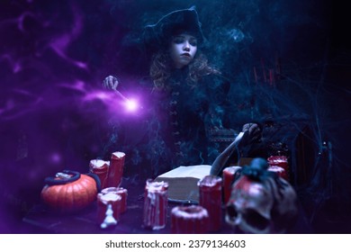 Cuentos de brujas. Halloween. Una bella y joven bruja hace magia con una varita mágica y un libro de hechizos, sentada en su guarida a la luz de las velas.