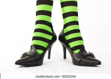 Witch's green and black striped legs with heels together and toes pointing out, white background.