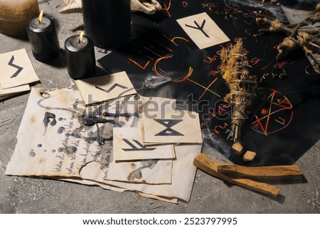 Witch's magic attributes with burning candles on grunge background, closeup