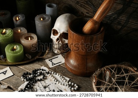 Witch's magic attributes with burning candles on dark wooden table, closeup