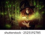 A witch-sorceress with red hair, dressed in a black dress and a big black hat, casts a spell with a magic wand and a book of spells, standing in a dense forest. Halloween.