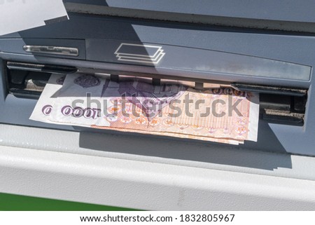 Withdraw money from ATM. 100 ISK banknotes at ATM machine.
