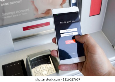 Withdraw Money From An ATM Without Using A Credit Card. Person Holding A Phone With A Login Screen For Mobile Banking.