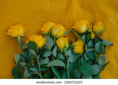 Withered Yellow Roses On Yellow Linen Fabric.