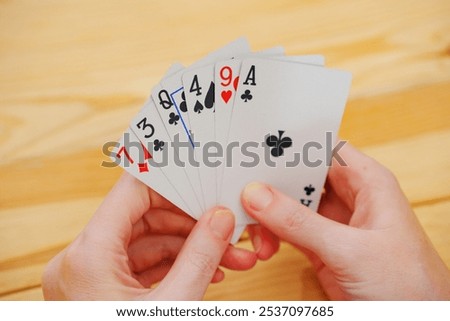 without a face. Hands of a man in a white t-shirt with cards during the game. gambling. A board game for spending leisure time with friends and family.
