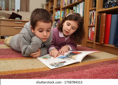 Witney, Oxfordshire, UK 01 19 2013 A Big Sister Reads A Book To Her Little Brother