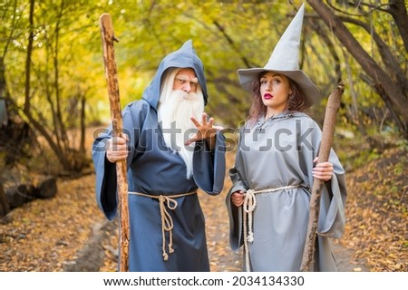 Wizard and sorceress in the autumn forest. Elderly man and woman in carnival costumes for halloween