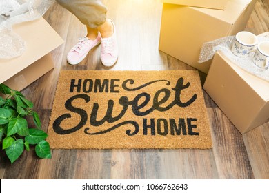 Wman in Pink Shoes and Sweats Standing Near Home Sweet Home Welcome Mat, Boxes and Plant. - Powered by Shutterstock