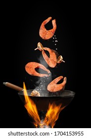 Wok Pan With Smoke Above Fire Is Frying Salmon Steaks With Garlic Against Black Studio Background. Cooking Concept. Close Up