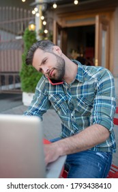 Woking Remotely. Bearded Handsome Male Talking On Phone, Typing On His Laptop In Open Air Cafe