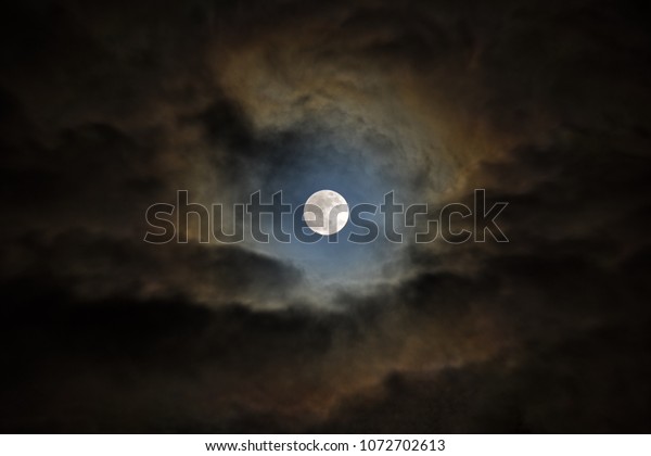 Wolf moon. The moon looks through an opening in\
the clouds.