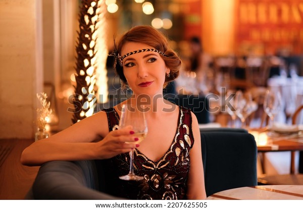 Woman in 1920\
style clothes with a glass of wine. Beautiful girl retro flapper\
style retro vintage roaring 20s.\
