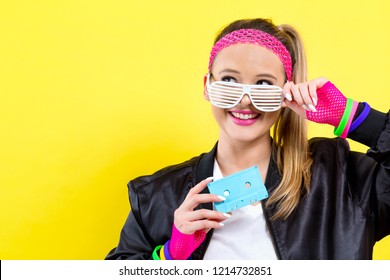 Woman in 1980's fashion holding a cassette tape on a split yellow background