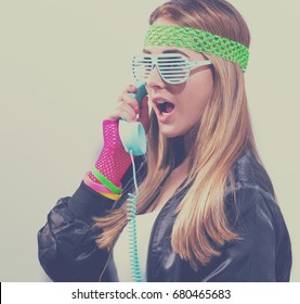 Woman in 1980's fashion with old fashioned phone on a white background