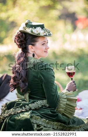 Woman in 19th century costume near waterfall in park in autumn