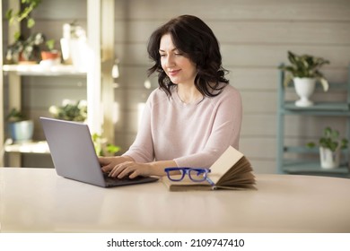 Woman 35-40 years old, works in a laptop at home, online work. High quality photo