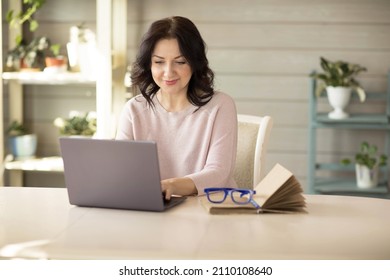 Woman 35-40 years old, works in a laptop at home, online work. High quality photo