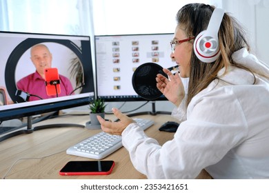 woman 40-45 years old, pretty female blogger sits in front of computer with green screen in front of microphone, emotionally talks on topic of business, communication during quarantine covid 19