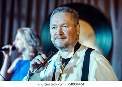 A Woman Of 40-45 Years Old, A Singer, Sings Into A Microphone. Man With Saxophone.