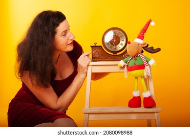 A Woman Of 50 Years Old On The Holiday New Year And Christmas Sits In The Background Of The Studio With A Clock Chime Chimes 2022