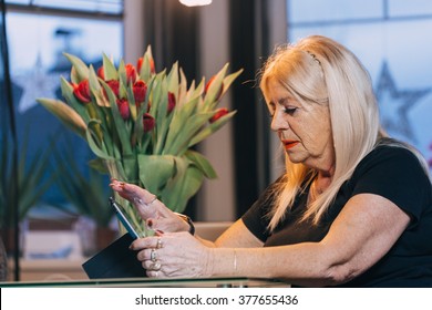 Woman 65-70 Years Old Using Ipad Tablet Pc Computer At Home