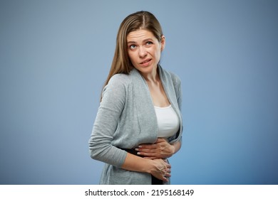 Woman With Abdominal Pain With Hands On Her Stomach Looking Up. Isolated Female Portrait On Blue.