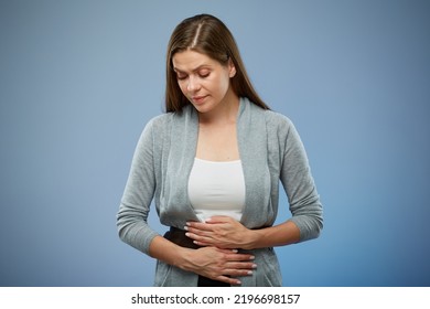 Woman With Abdominal Pain With Hands On Her Stomach Looking Down. Isolated Female Portrait On Blue.