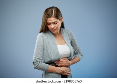 Woman With Abdominal Pain With Hands On Her Stomach Looking Down. Isolated Female Portrait On Blue.