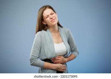 Woman With Abdominal Pain With Hands On Her Stomach. Isolated Female Portrait On Blue.