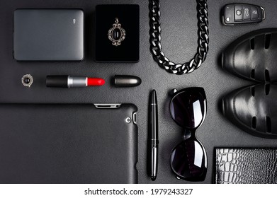 Frauenzubehör im Business-Stil, roter Lippenstift, Gadgets, Schuhe, Schmuck, Autoschlüssel, Sonnenbrillen und andere Luxusgeschäftstilithähne auf schwarzem Hintergrund, Modebranche, Draufsicht