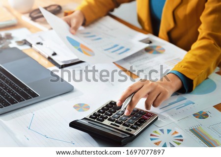 Woman accountant use calculator and computer with holding pen on
