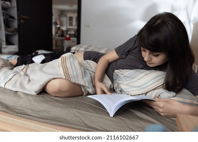 Woman With ACL Surgery Reading In Bed At Home.