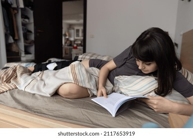 Woman With ACL Surgery Reading In Bed At Home.