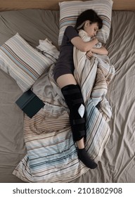 Woman With ACL Surgery Sleeping In Bed At Home.