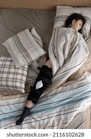 Woman With ACL Surgery Sleeping In Bed At Home.