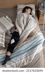 Woman With ACL Surgery Sleeping In Bed At Home.