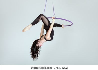 Woman acrobat on a hula hoop does tricks.