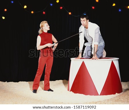 Woman acting like a ringmaster dominating a man