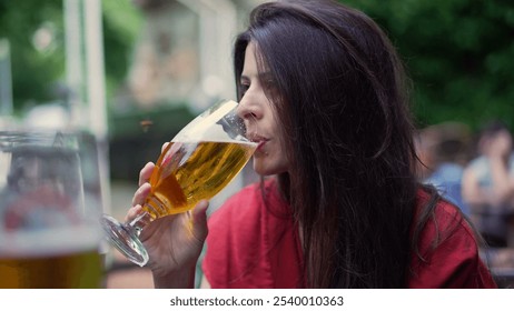 Woman actively drinking beer outdoors, holding a glass to her lips. relaxation and enjoyment in a casual outdoor setting, lifestyle moment - Powered by Shutterstock