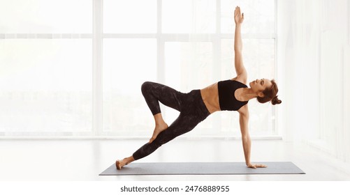 A woman is actively engaged in a yoga pose on a yoga mat, showcasing flexibility, balance, and strength. She demonstrates proper form and focus, embodying the practice of yoga. - Powered by Shutterstock