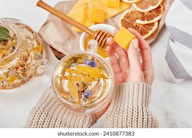 Woman add honey to organic mountain blend - calming herbal elixir -wellness retreat with herbal infusions.